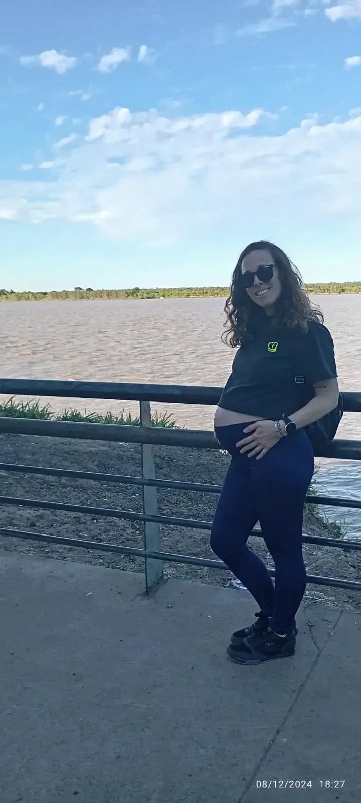 Mariana embarazada, sonriendo junto al río